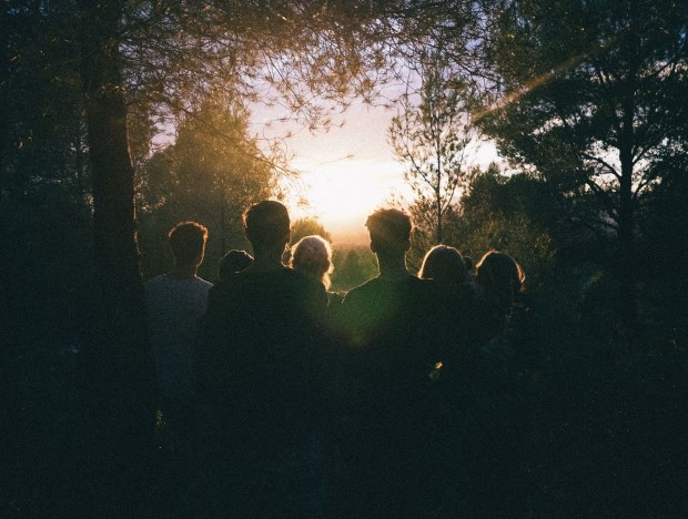 Silhouettes of people in a forest at sunset.